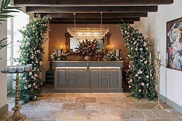 A bar with a chandelier and flowers behind it