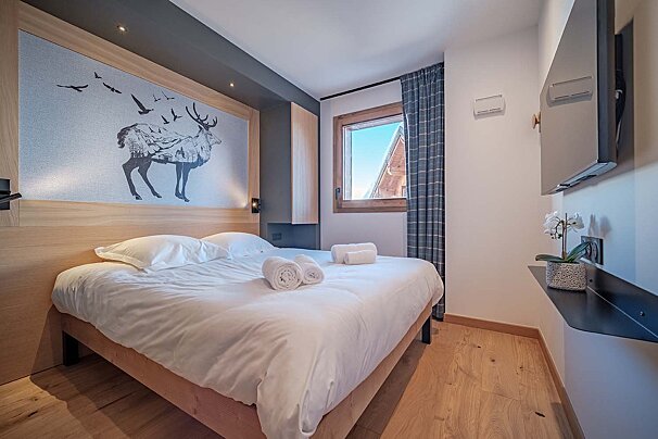 A small bedroom with a bed and a television