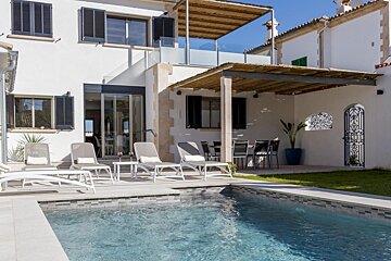 A white house with a swimming pool in front of it