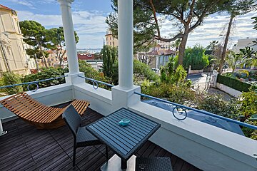 A balcony with a table and chairs and a view of a city