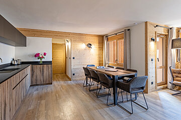 A kitchen with a table and chairs and a vase of flowers