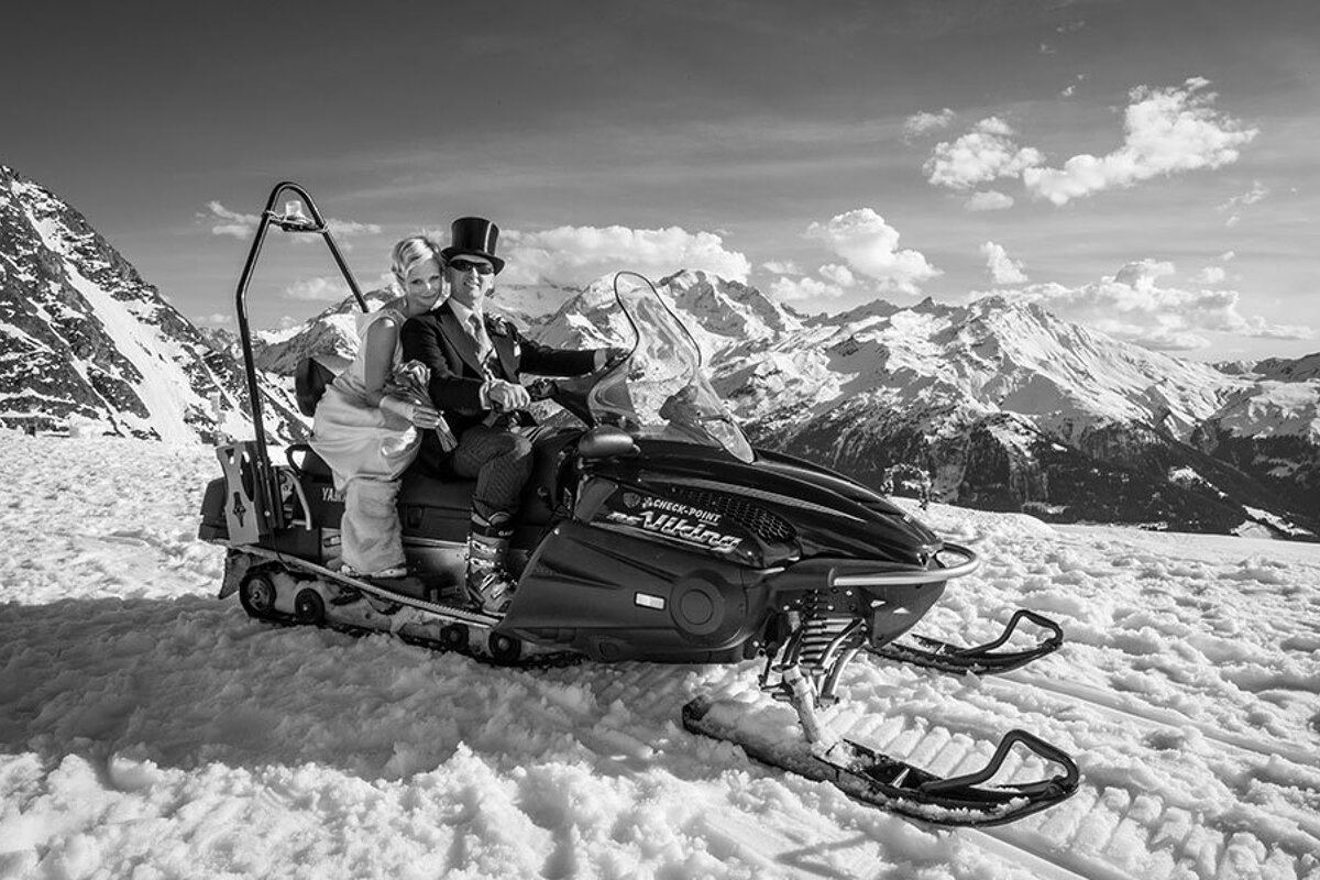 A black and white photo of a bride and groom on a polaris snowmobile
