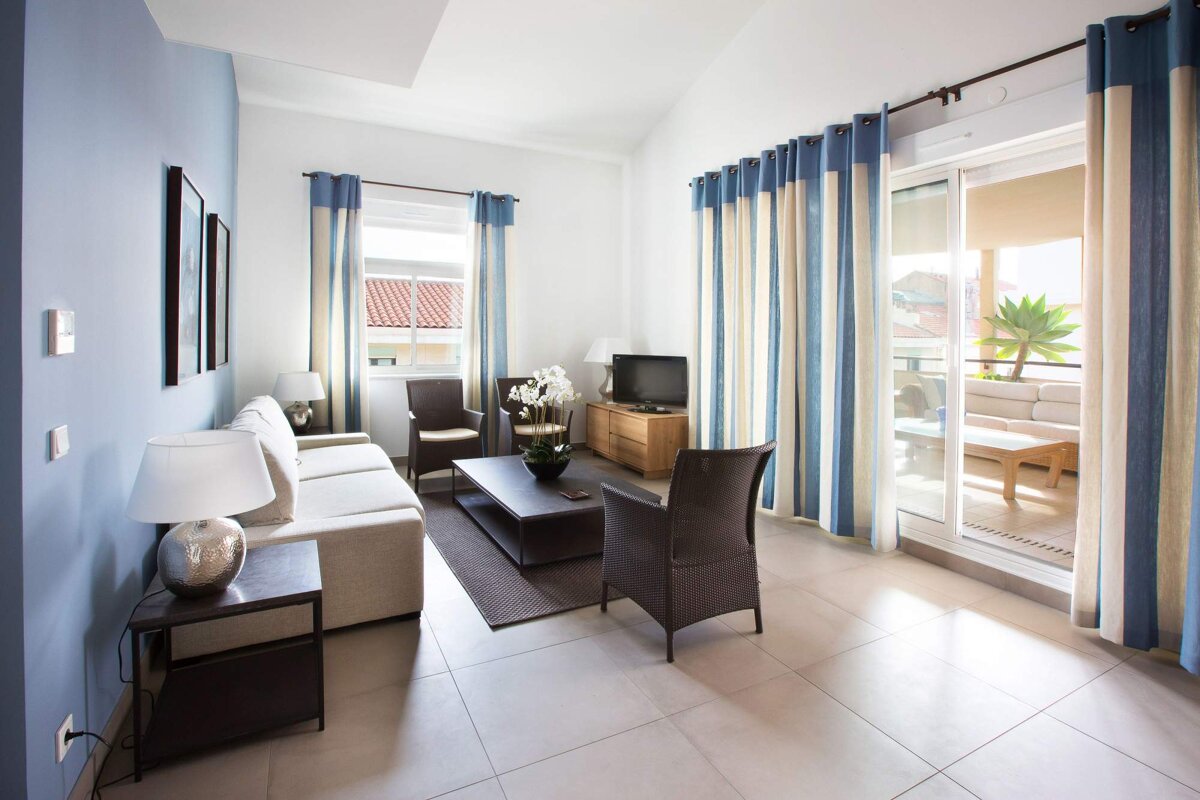 A living room with blue and white curtains and a sliding glass door