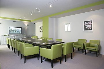 A conference room with a long table and green chairs