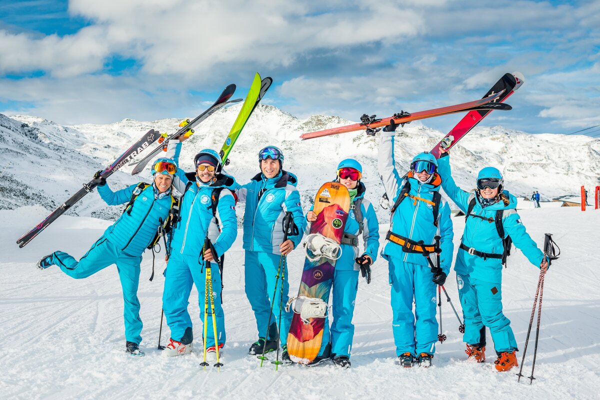 A group of skiers are posing for a picture and one of their skis has the word xtrem on it