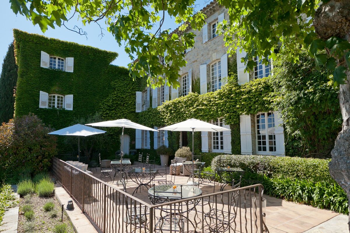 A patio with tables and chairs and umbrellas in front of a building