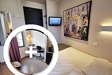 A hotel room with a tv and a painting on the wall