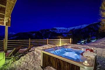A hot tub in the snow with mountains in the background