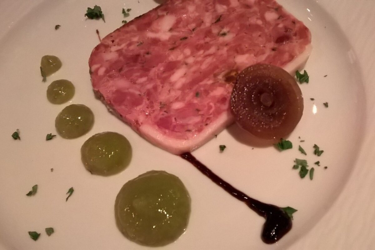 A white plate with a piece of meat and grapes on it