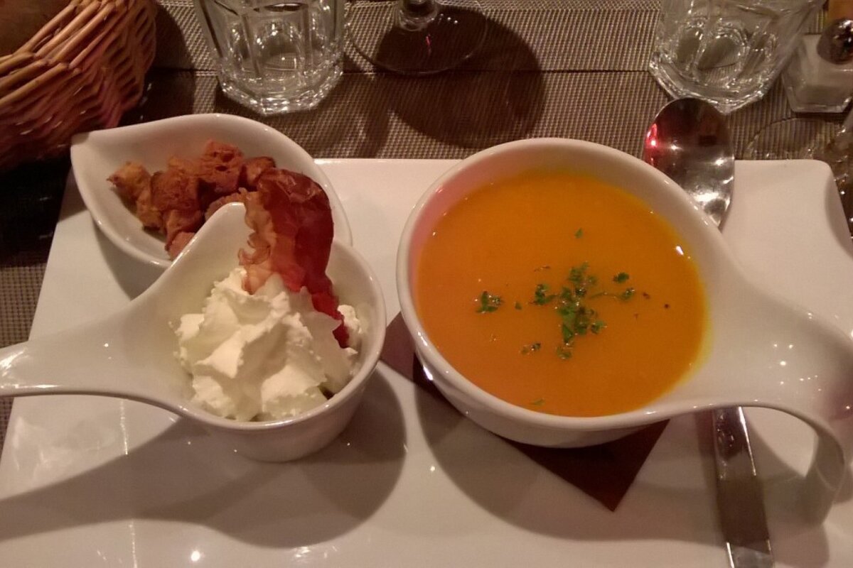 A bowl of soup next to a bowl of whipped cream