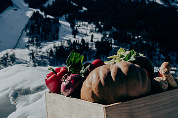 A wooden box filled with vegetables in the snow