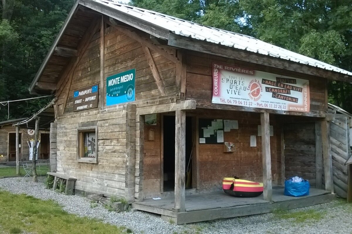 large wooden house with signs on the outside and gravel around it with a small raft in front