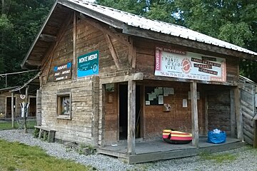 large wooden house with signs on the outside and gravel around it with a small raft in front