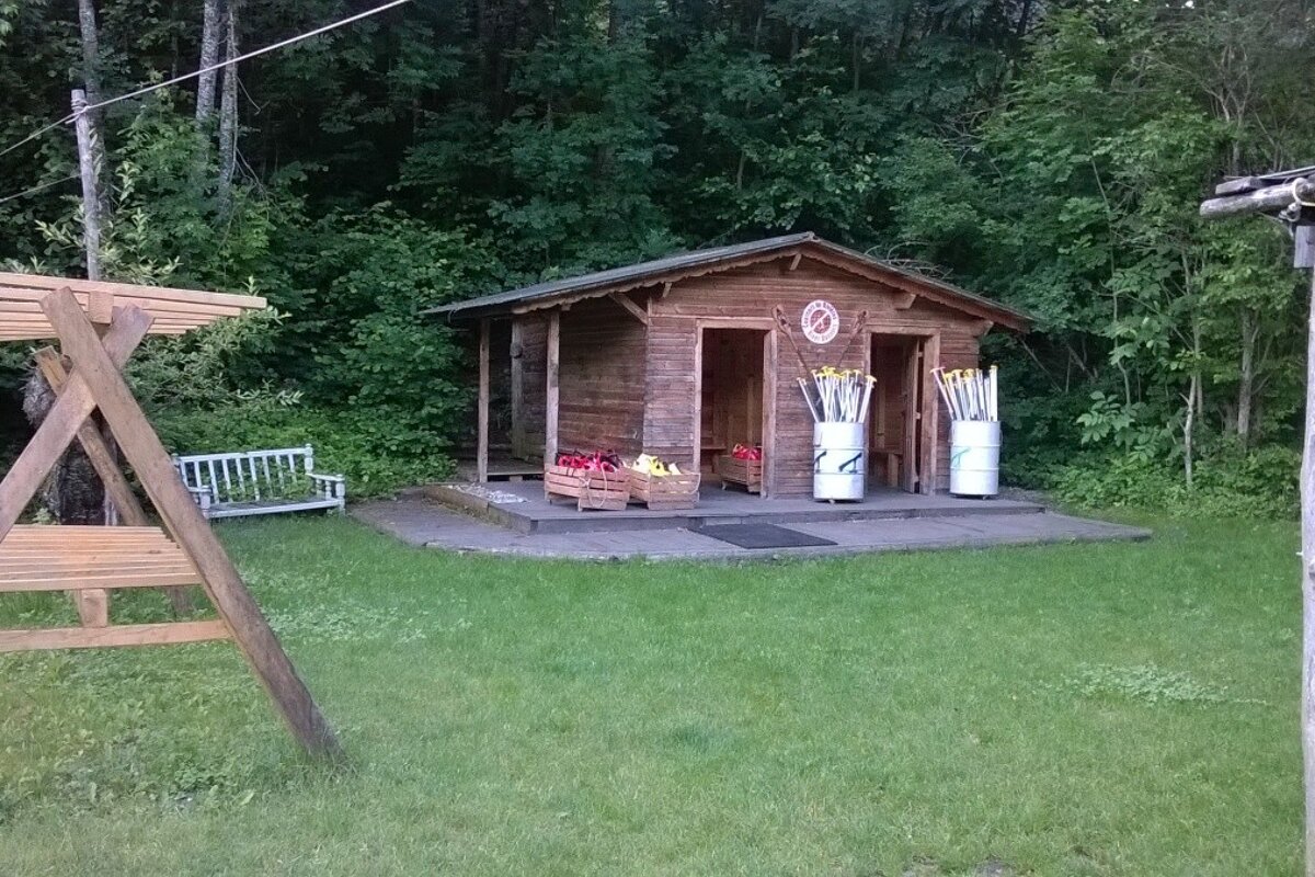 changing rooms in a wooden hut with drums of paddles in front and some grass and trees