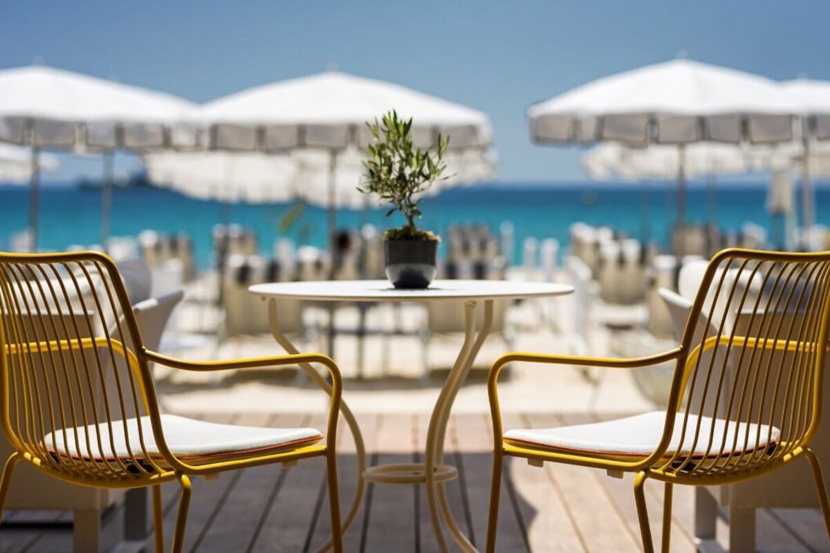 Two yellow chairs sit at a table with a potted plant on it