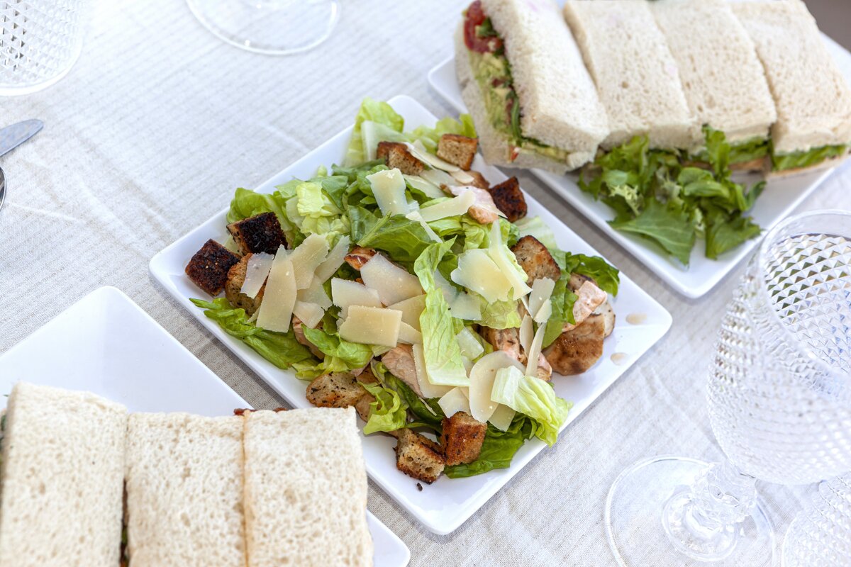 A salad on a plate next to a sandwich on a plate