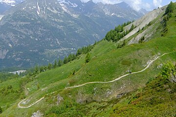 a tiny mountain biker on a far hillside in sowtzerland