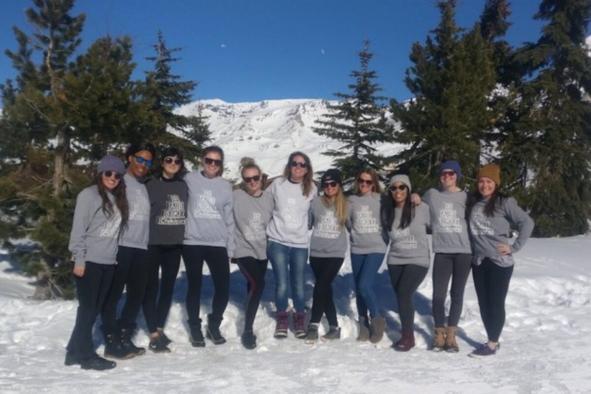 A group of women wearing the north face sweatshirts pose for a photo