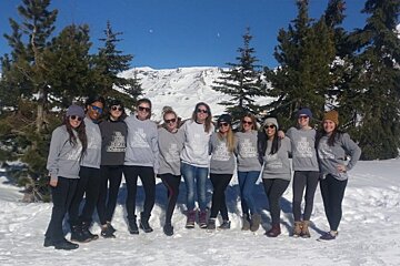 A group of women wearing the north face sweatshirts pose for a photo