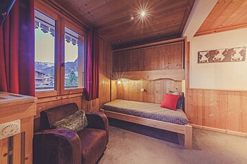 A bedroom with a single bed and a chair