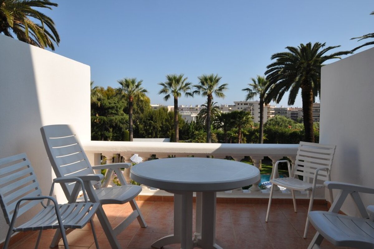 A white table and chairs on a balcony overlooking palm trees