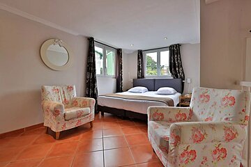 A bedroom with a bed two chairs and a mirror