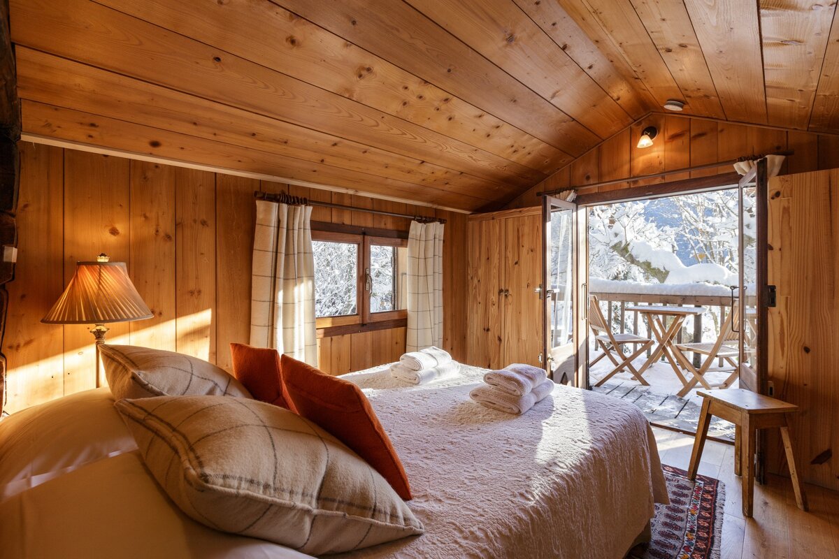 A wooden bedroom with a bed and a lamp