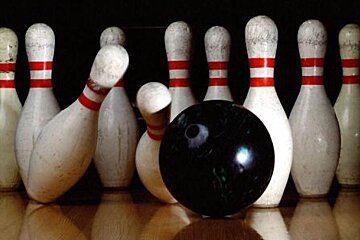 A bowling ball is hitting a pin on a bowling alley