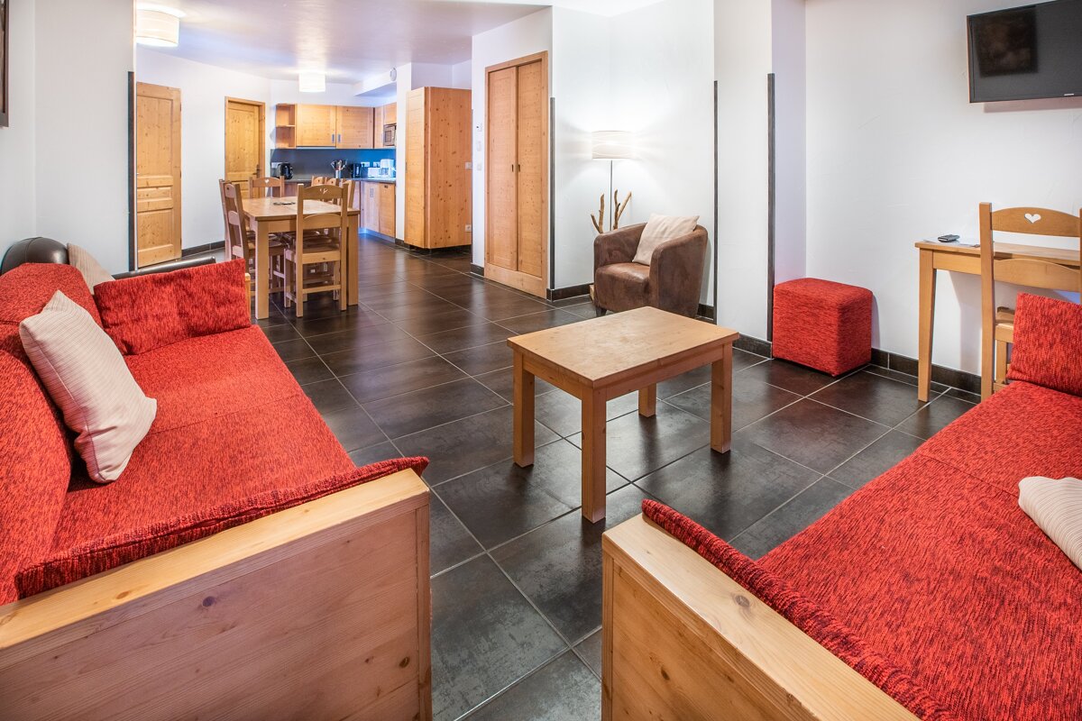 A living room with a red couch and a wooden table