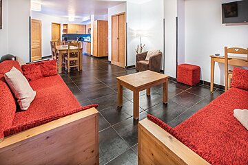 A living room with a red couch and a wooden table