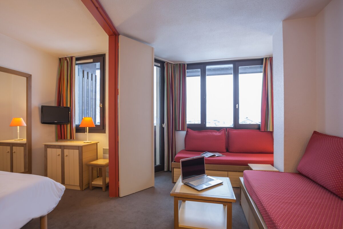 A hotel room with a couch and a laptop on a table