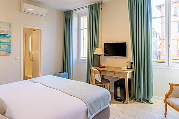 A hotel room with a bed a desk and a television