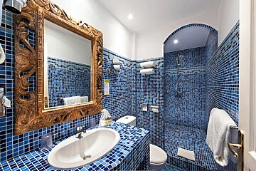 A bathroom with blue tiles and a mirror