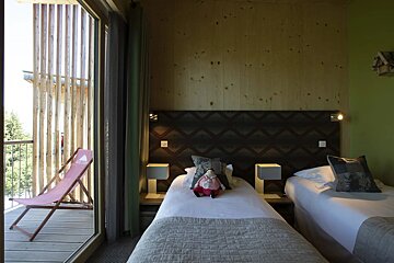 A bedroom with two beds and a pink chair