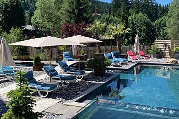 A large swimming pool surrounded by chairs and umbrellas