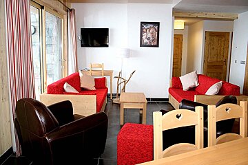 A living room with a red couch and a picture of a cow on the wall