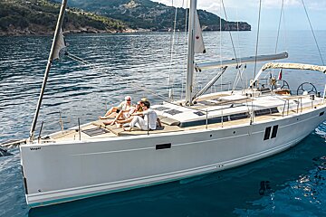 A group of people sit on the deck of a sailboat named voyager