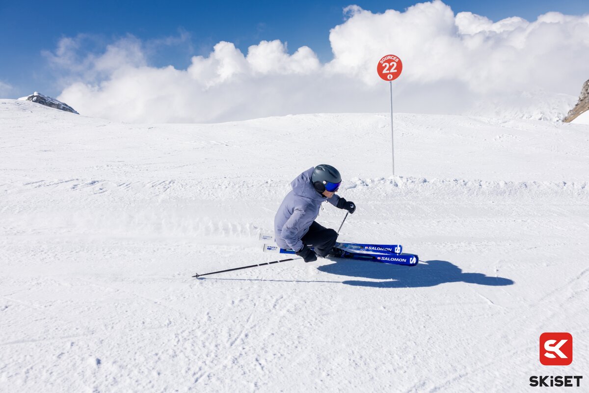 A person skiing down a snowy slope with a sign that says salomon on it