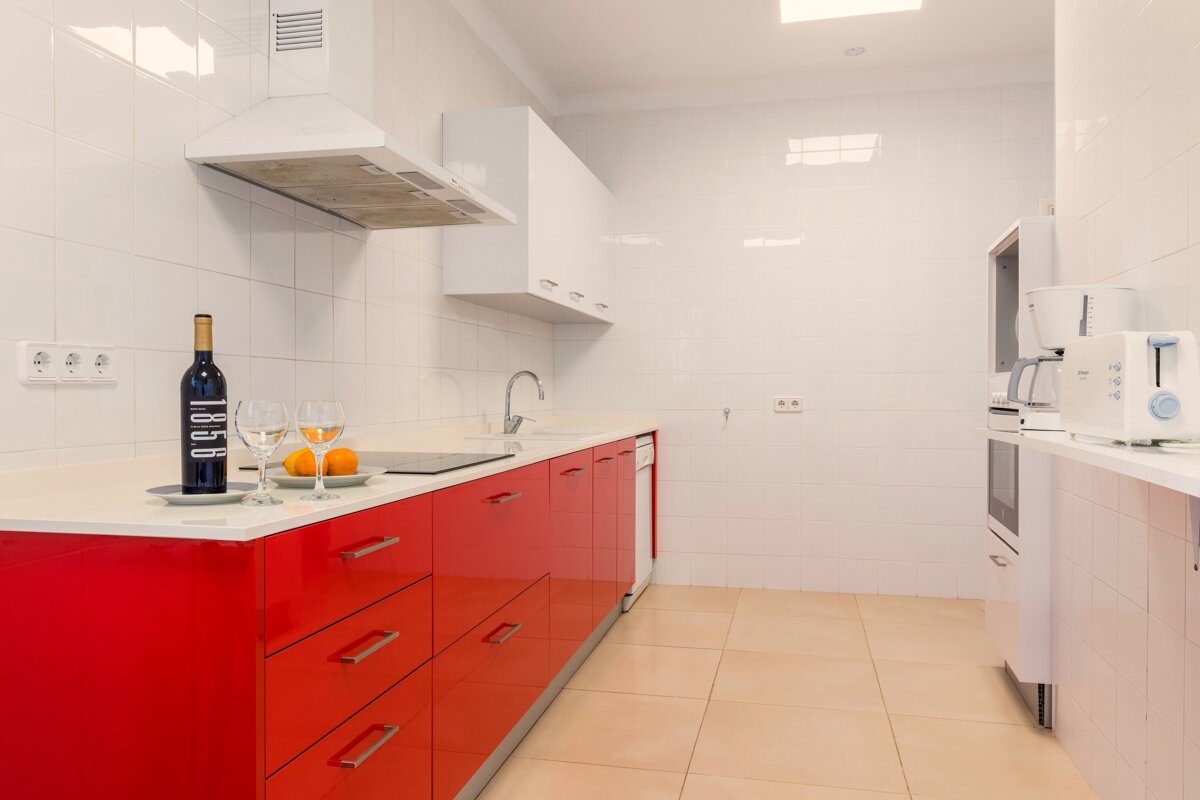 A kitchen with red cabinets and a bottle of 1868 wine