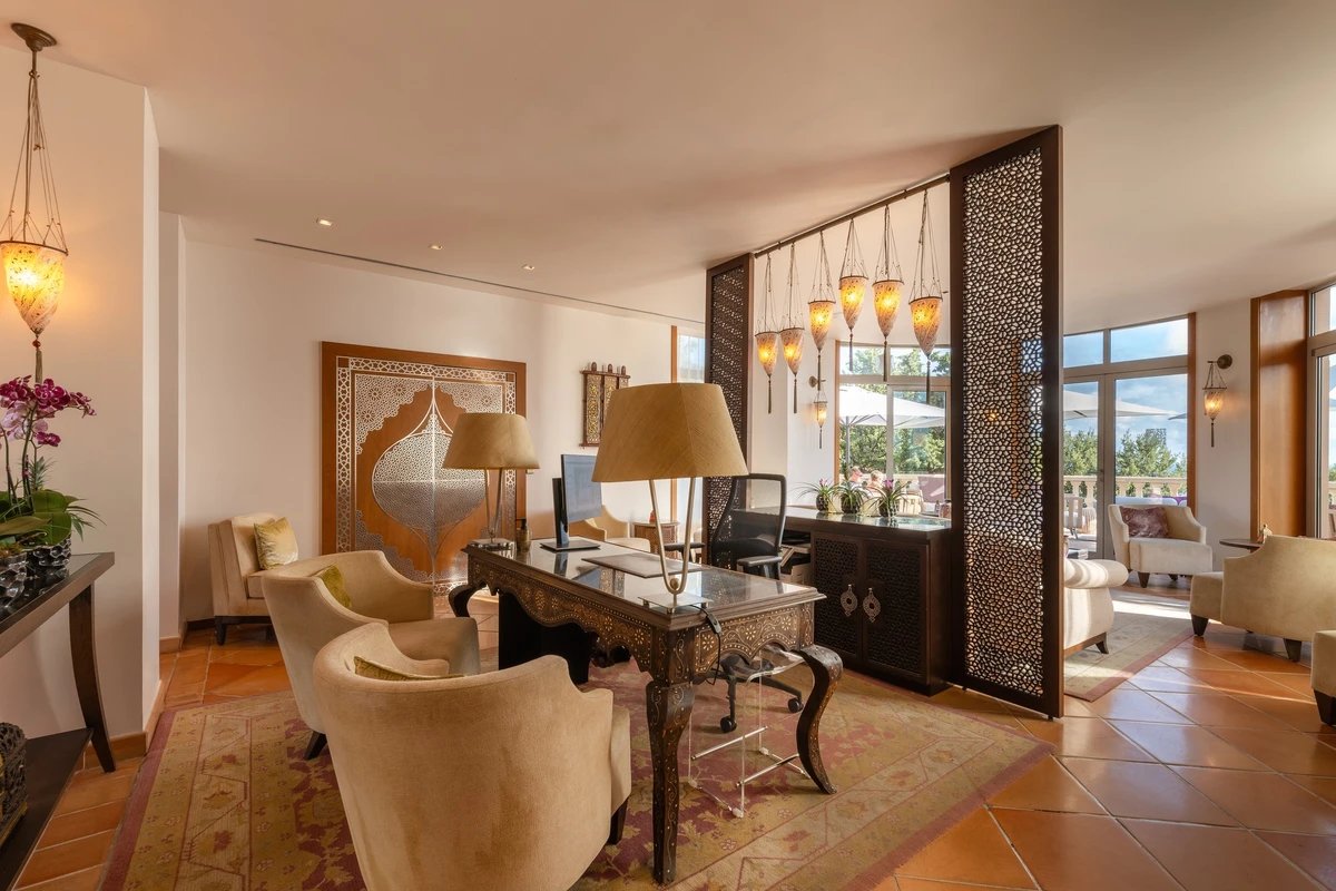 A living room with a desk and chairs and lamps