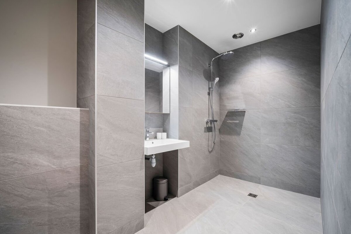 A bathroom with a walk in shower and a sink