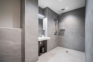 A bathroom with a walk in shower and a sink