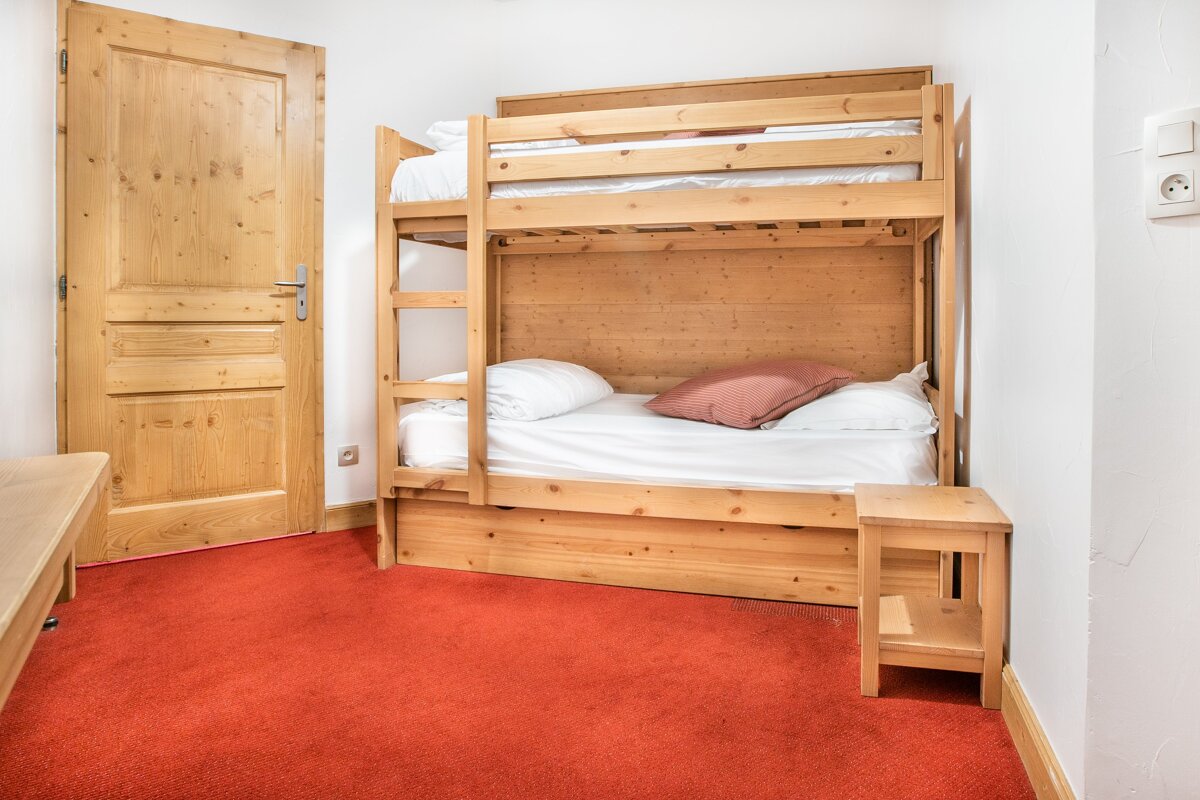 A bunk bed in a bedroom with a red carpet
