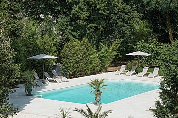 A large swimming pool surrounded by chairs and trees