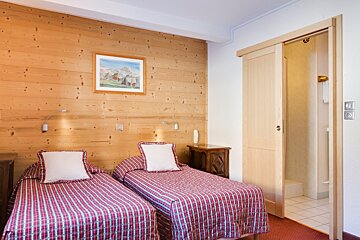 A bedroom with two beds and a picture on the wall