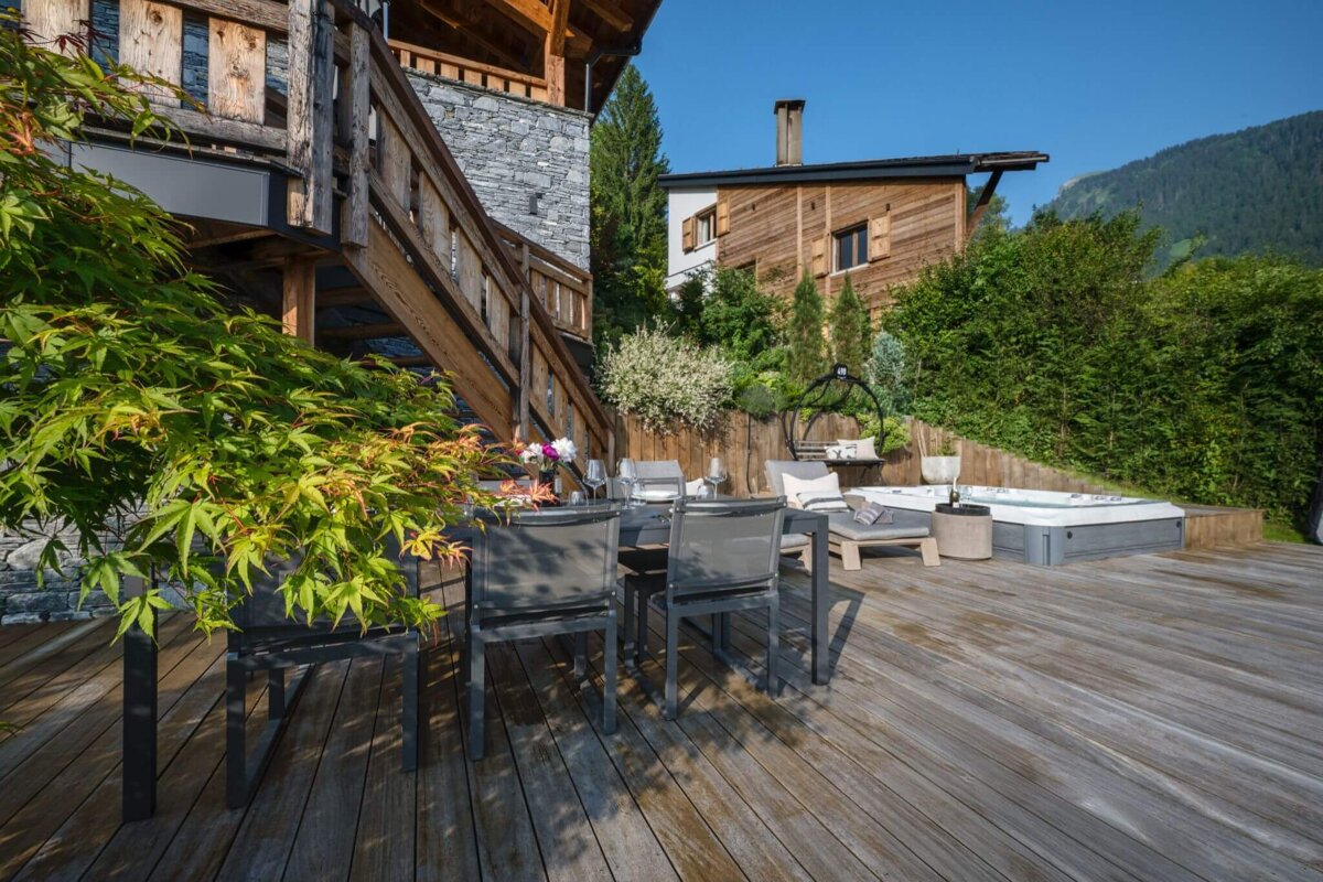 A wooden deck with a table and chairs and a hot tub