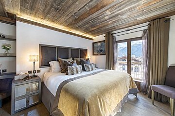 A bedroom with a large bed and a painting on the wall