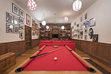 A pool table in a room with pictures on the wall