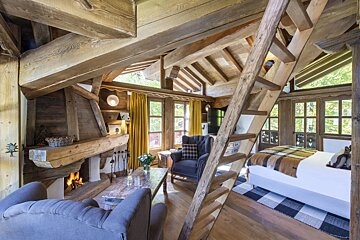A living room with a fireplace and stairs leading up to a bedroom