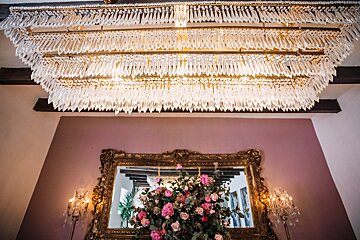 A large crystal chandelier hangs from the ceiling above a mirror